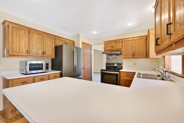 kitchen featuring a sink, light countertops, a peninsula, and stainless steel appliances