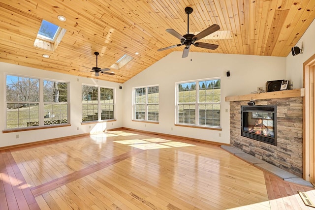 unfurnished living room with a ceiling fan, a skylight, a fireplace, light wood finished floors, and wood ceiling