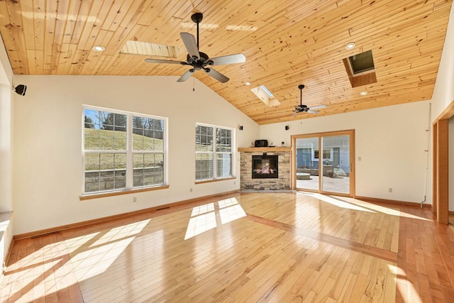 unfurnished living room featuring a ceiling fan, visible vents, high vaulted ceiling, a skylight, and a fireplace