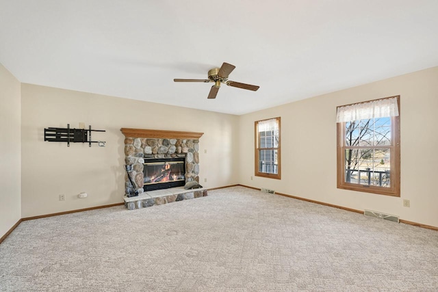 carpeted living area featuring visible vents, baseboards, a fireplace, and a ceiling fan