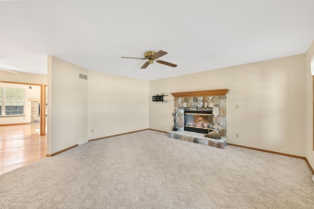 unfurnished living room with baseboards, carpet, ceiling fan, and a fireplace