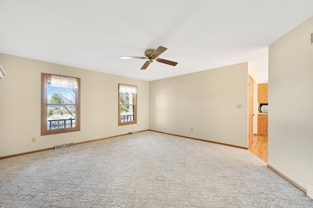 unfurnished room with visible vents, baseboards, carpet, and a ceiling fan