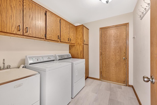 laundry area with a sink, baseboards, cabinet space, and separate washer and dryer