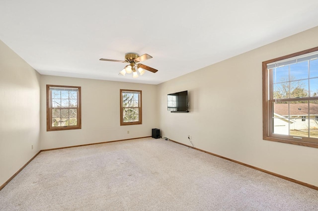 spare room with light colored carpet, baseboards, and ceiling fan