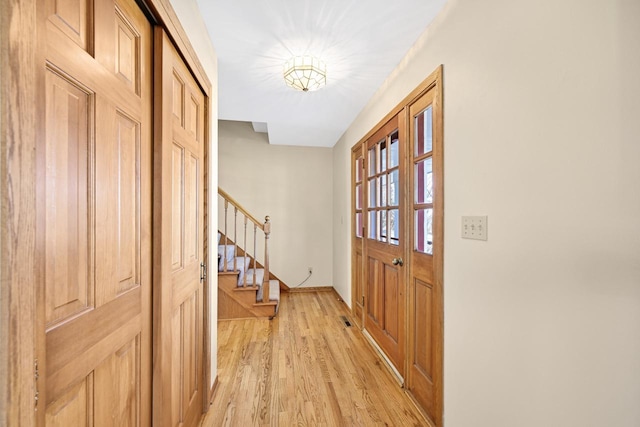 entrance foyer featuring stairs, baseboards, and light wood finished floors