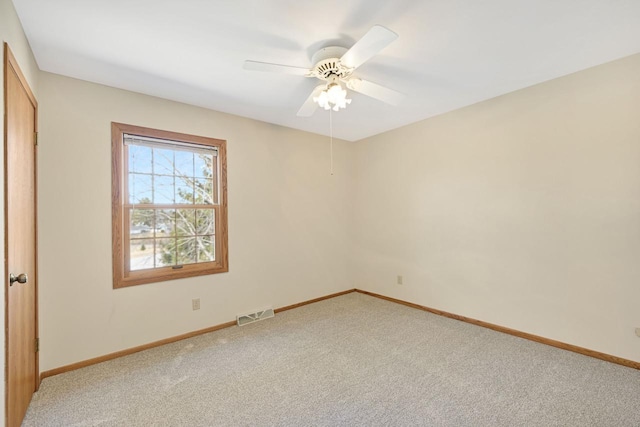 spare room featuring visible vents, light carpet, baseboards, and ceiling fan