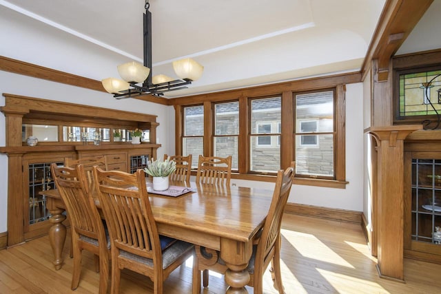 dining area with baseboards, light wood-style floors, a chandelier, and a fireplace