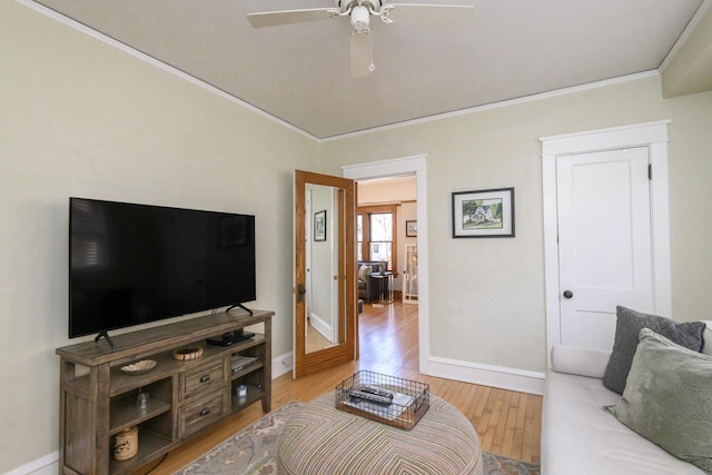 living area with light wood-style flooring, baseboards, crown molding, and ceiling fan