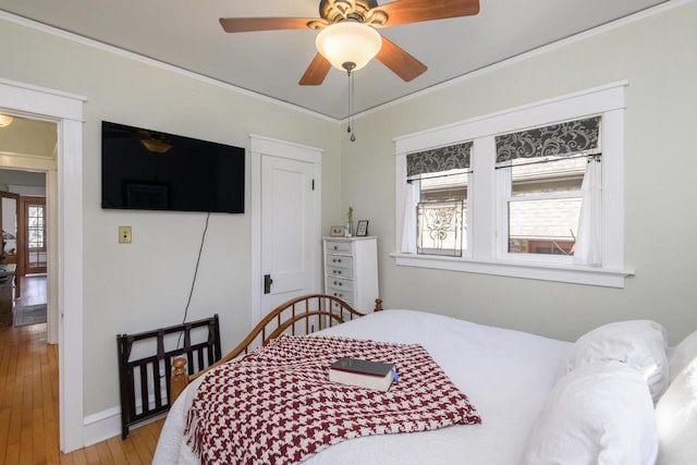 bedroom featuring a ceiling fan, baseboards, light wood-style floors, and crown molding