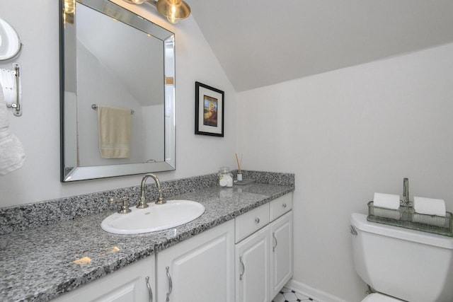 bathroom with toilet, vanity, baseboards, and vaulted ceiling