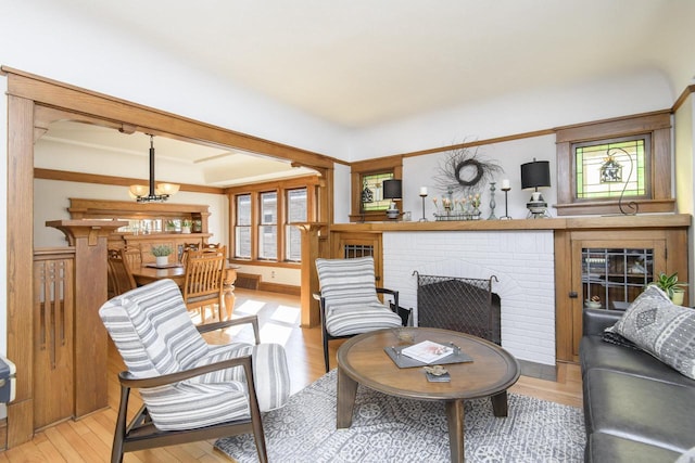 living area with a notable chandelier, light wood-style flooring, and a fireplace