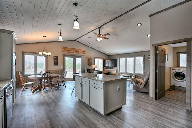 kitchen with lofted ceiling, stainless steel dishwasher, open floor plan, wood ceiling, and washer / dryer