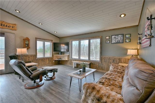 living room with a wainscoted wall, wood walls, and lofted ceiling