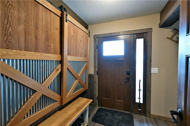 foyer featuring wood finished floors, a textured ceiling, and a barn door