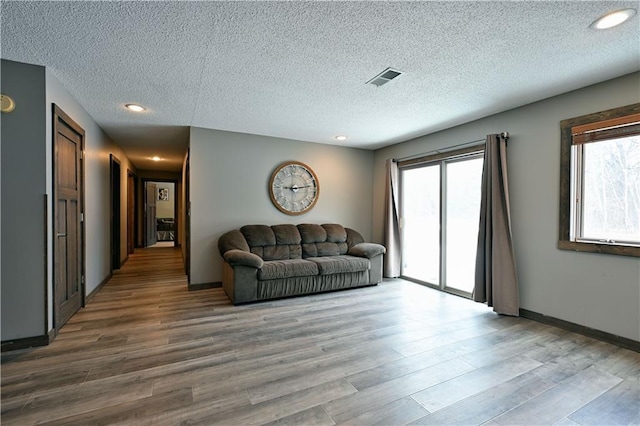 living area featuring a textured ceiling, wood finished floors, visible vents, and recessed lighting