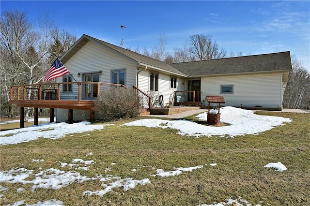 snow covered back of property featuring a lawn and a wooden deck