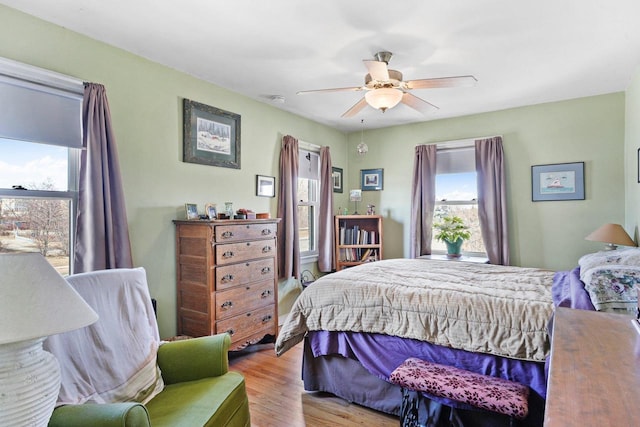 bedroom with multiple windows, wood finished floors, and a ceiling fan