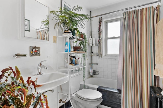 bathroom featuring toilet, radiator, shower / bath combo, and a sink