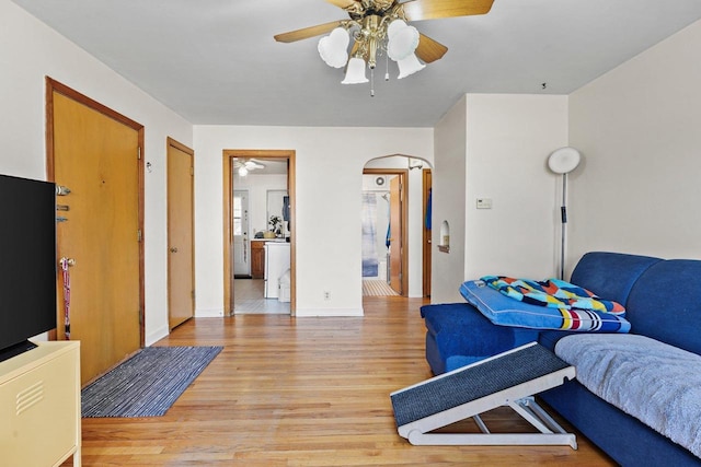 bedroom with arched walkways, ensuite bathroom, a ceiling fan, light wood-type flooring, and baseboards