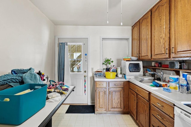 kitchen featuring a sink, white dishwasher, brown cabinets, and light countertops