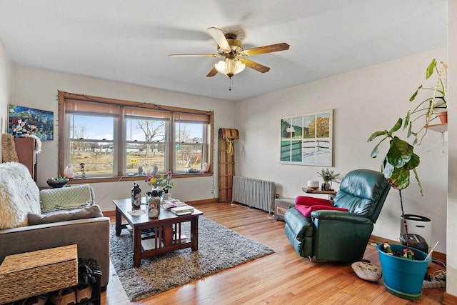 living room featuring a ceiling fan, radiator, baseboards, and wood finished floors