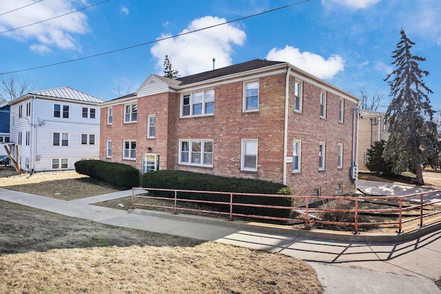 view of front of home featuring fence and brick siding