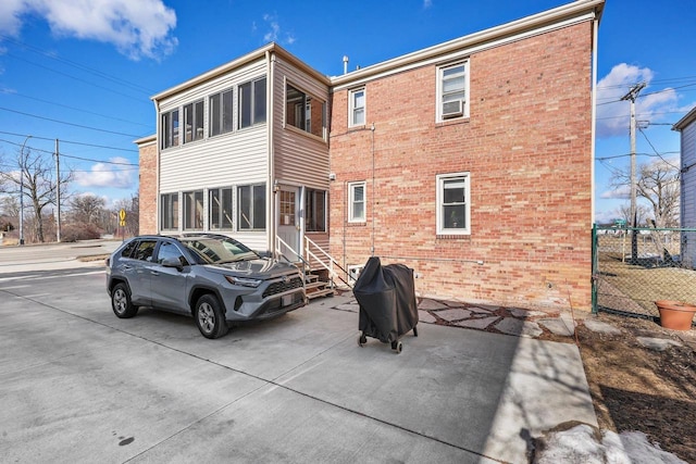 rear view of house with entry steps, fence, and brick siding