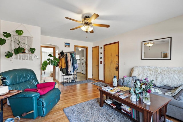 living area with a ceiling fan, arched walkways, baseboards, and wood finished floors