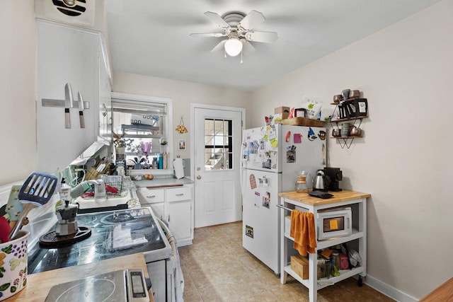 kitchen featuring ceiling fan, white cabinetry, baseboards, light countertops, and freestanding refrigerator