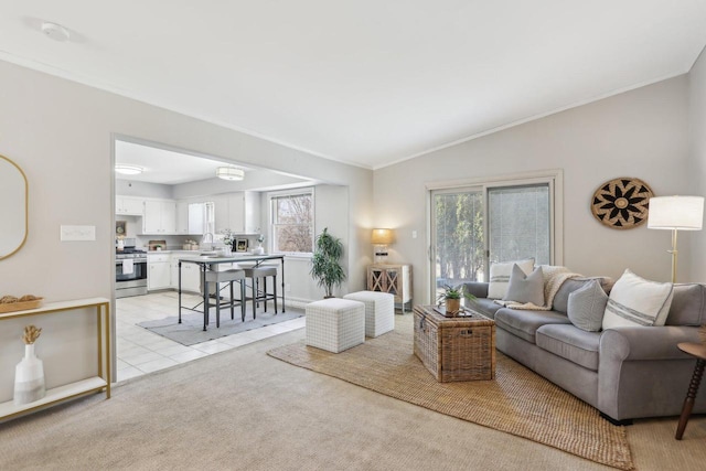 living area featuring vaulted ceiling, light tile patterned floors, crown molding, and light carpet