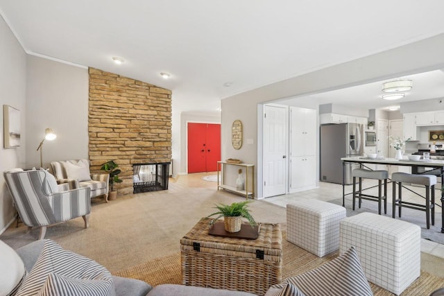 living room with vaulted ceiling, crown molding, a fireplace, and light colored carpet