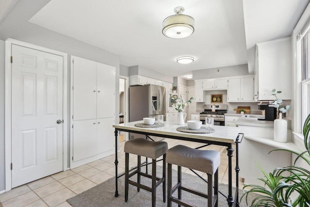 kitchen featuring a sink, appliances with stainless steel finishes, white cabinets, light countertops, and light tile patterned floors