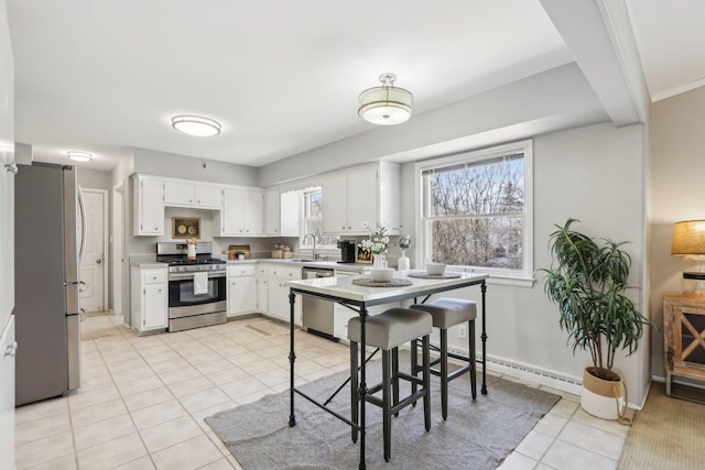 kitchen with light tile patterned floors, baseboards, stainless steel appliances, light countertops, and white cabinets