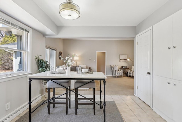 dining space featuring light tile patterned floors, baseboards, baseboard heating, and light carpet