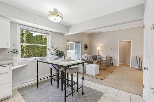 dining room featuring baseboards, light carpet, baseboard heating, and light tile patterned flooring