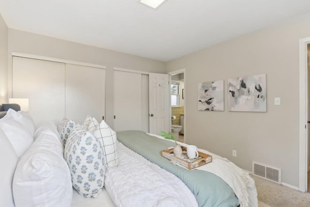 carpeted bedroom with baseboards, visible vents, and two closets