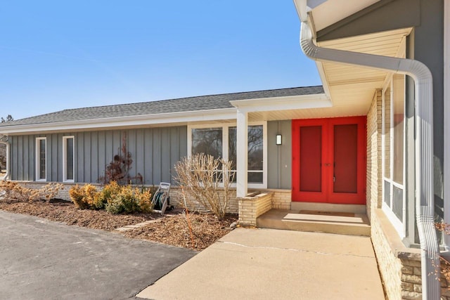 doorway to property featuring roof with shingles and board and batten siding