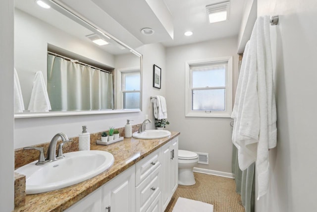 full bathroom with a sink, visible vents, toilet, and double vanity