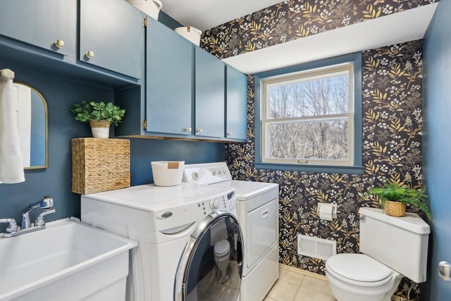 laundry area featuring wallpapered walls, washing machine and dryer, visible vents, and a sink