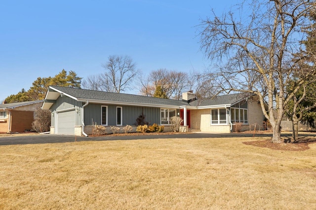 ranch-style home with a garage, driveway, a chimney, and a front yard