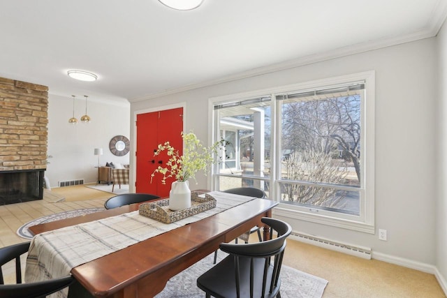 dining area with visible vents, a stone fireplace, crown molding, and a baseboard radiator