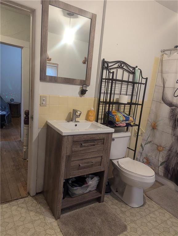 bathroom featuring toilet, vanity, and tile walls