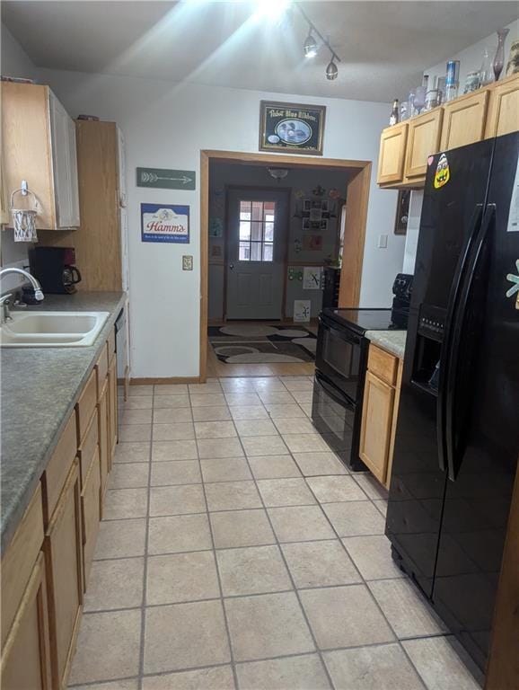 kitchen featuring light tile patterned floors, baseboards, a sink, black appliances, and track lighting