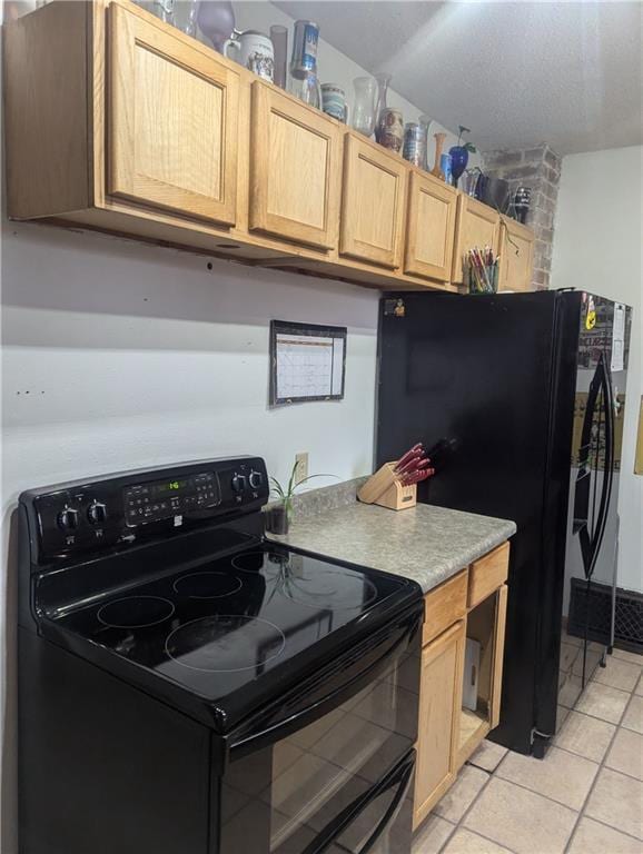 kitchen with black appliances, light brown cabinetry, light countertops, and light tile patterned flooring