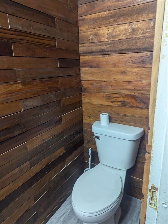 bathroom with wood walls and toilet