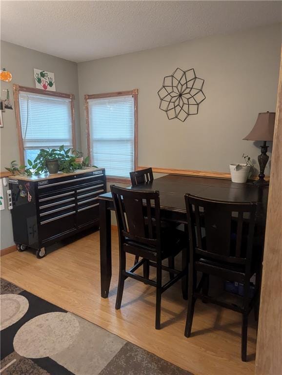 dining area featuring light wood-style floors and a textured ceiling