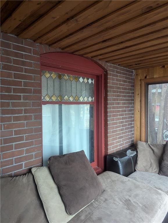 bedroom with brick wall, multiple windows, and wood ceiling