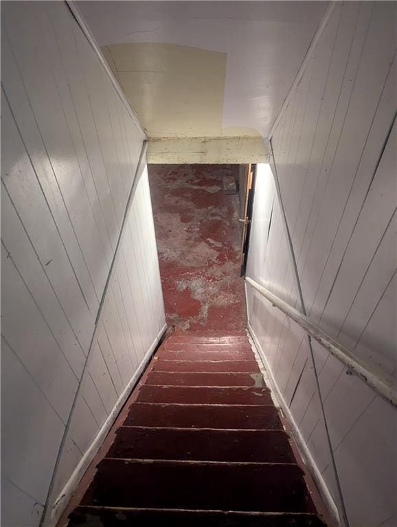 stairs featuring brick floor and wooden walls