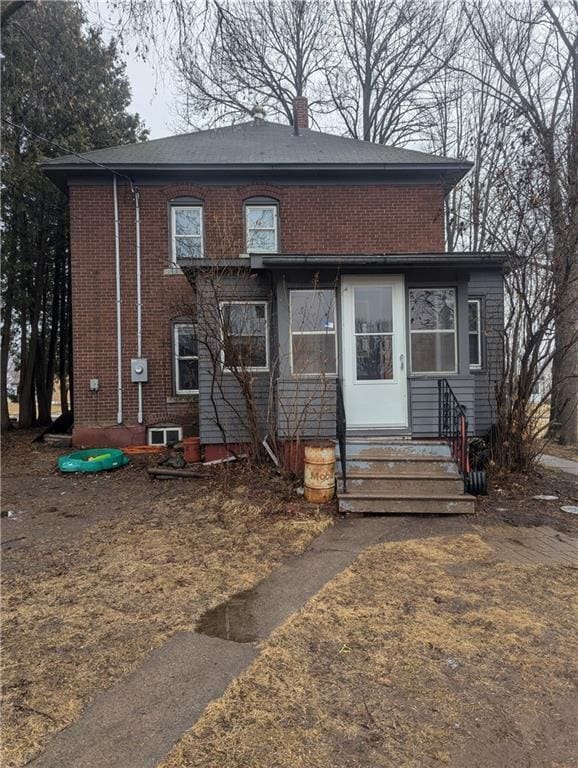 view of front of house featuring entry steps, brick siding, and a chimney