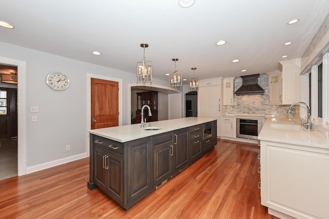 kitchen featuring custom range hood, stainless steel appliances, a sink, and light countertops